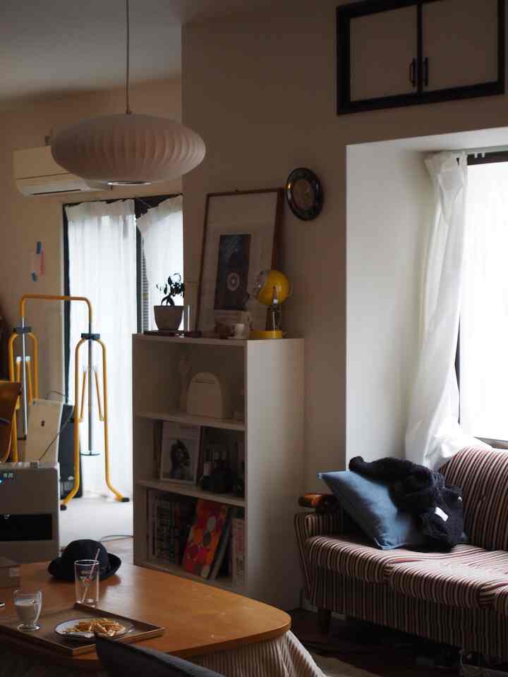 A warm-toned living room with white walls and curtains, a brown wooden coffee table, and a striped sofa