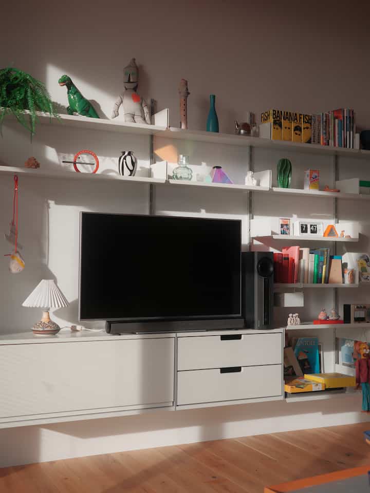 Bright white and natural color living room featuring organized TV stand and bookshelf with neat layout