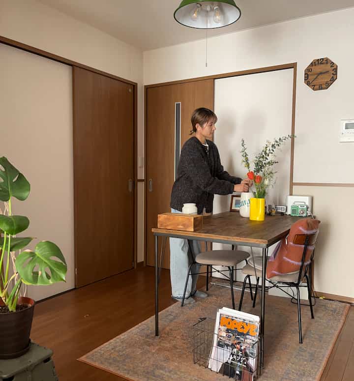 ナチュラルな色調の1LDKダイニング、木製テーブルと椅子、植物が配置された雰囲気のある空間