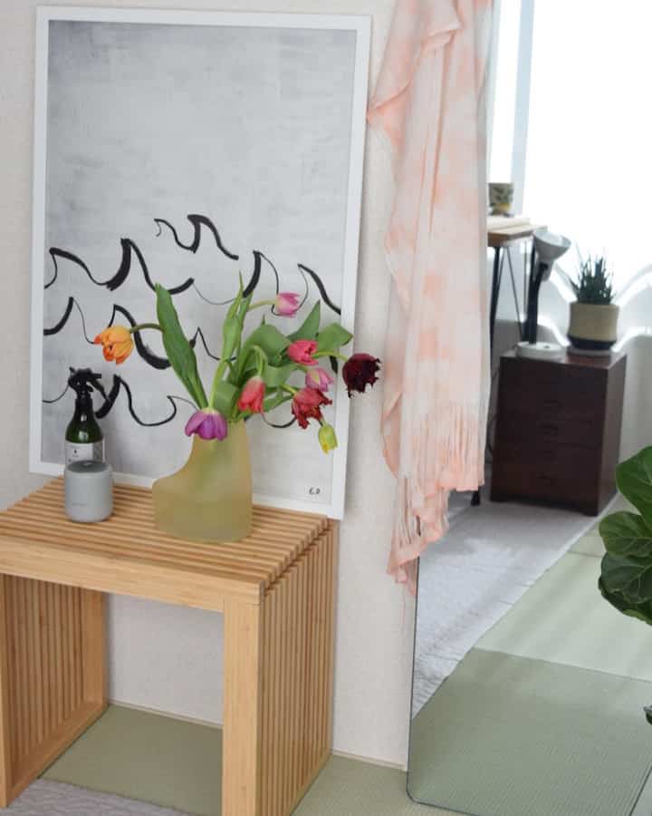 白とベージュのトーンのインテリア、竹製のベンチの上にカラフルなチューリップの花瓶が置かれた雰囲気のある空間