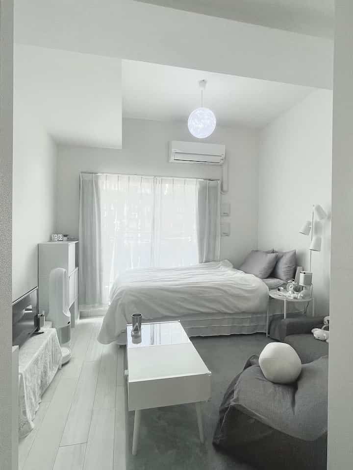 白とグレーのトーンが特徴の一人暮らし寝室、シンプルでホテルライクなインテリア