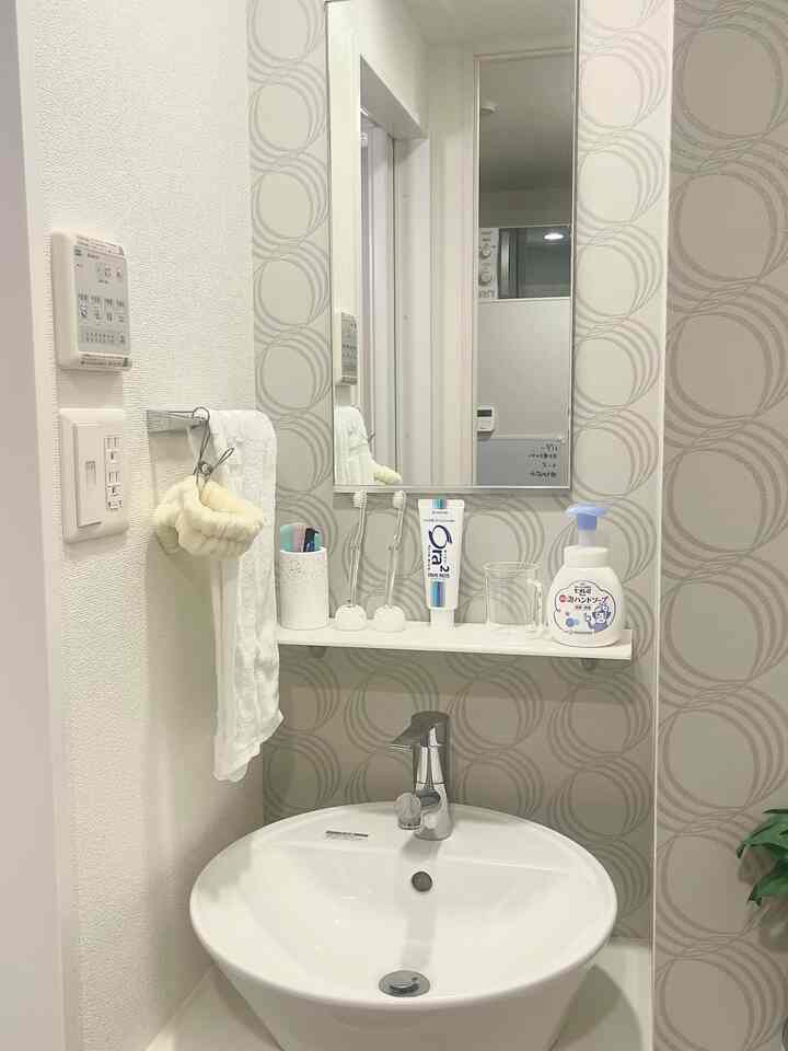 白を基調としたバスルームの洗面スペース、清潔感のあるシンプルなタオルと鏡が配置された実用的なインテリア