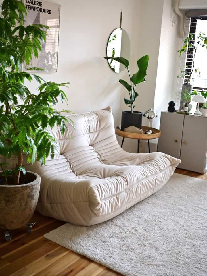 White and green themed living room featuring a soft sofa and lush plants creating a natural atmosphere