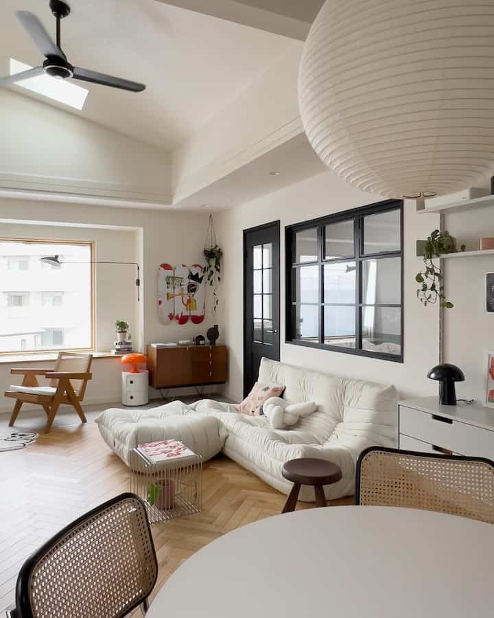 白とナチュラルな色調のリビング、ふかふかのソファと木製のアームチェアが柔らかな雰囲気を醸し出す印象的な空間