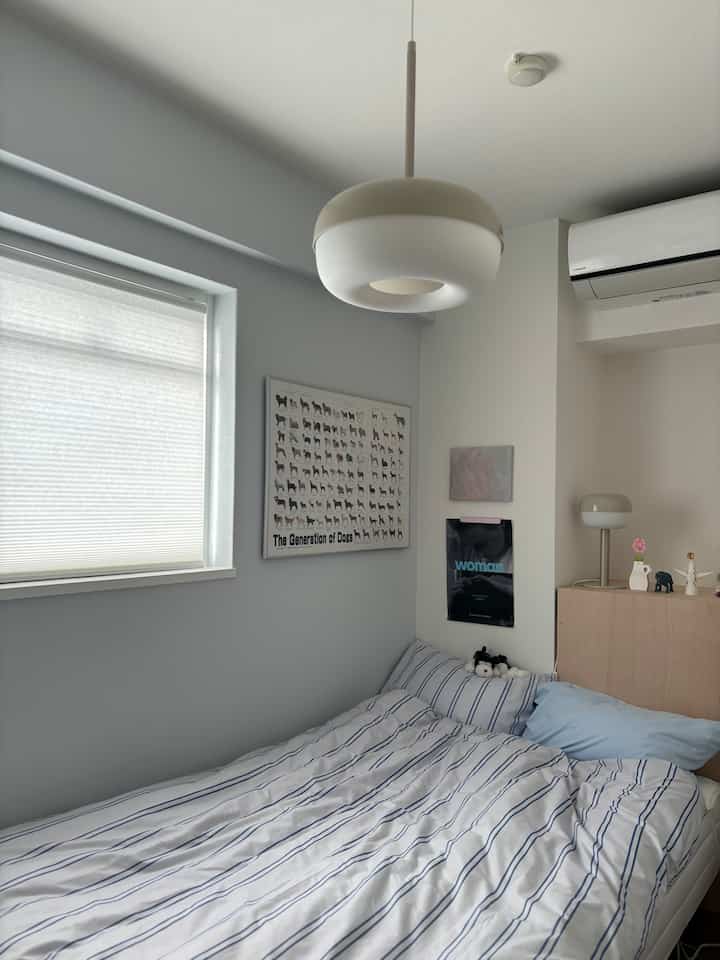 White and blue toned bedroom featuring striped bedding and simple lighting fixtures in a cozy space
