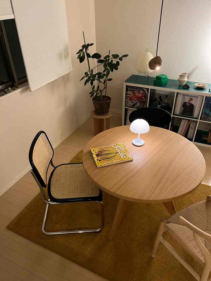 温かみのある木目調とナチュラルスタイルの二人用ダイニングルーム、丸テーブルとラタンチェアが配置された落ち着いた空間