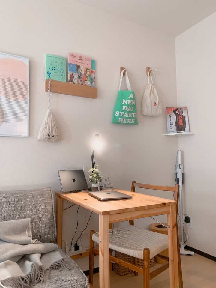 Bright wood tone natural 1-person home office space featuring desk, chair, grey sofa with cozy atmosphere