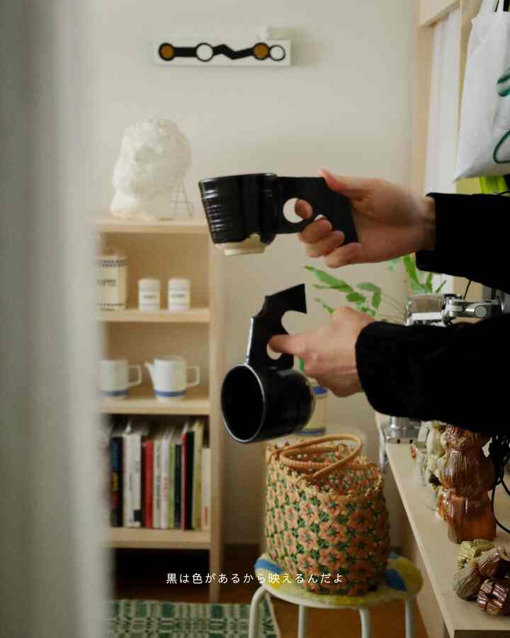 ナチュラルな色調の玄関、黒い現代陶芸のカップと木製の棚、植物が配置された雰囲気のあるインテリア