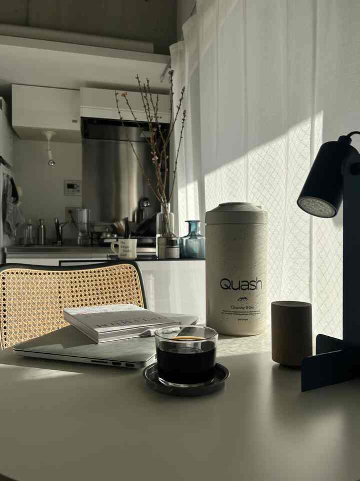 White and natural toned studio apartment kitchen-desk space, cozy home cafe vibe with coffee and cleaning supplies on table