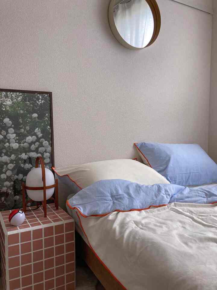 白と茶色のトーンの寝室、青い枕とタイルのサイドテーブルが配置された落ち着いた空間