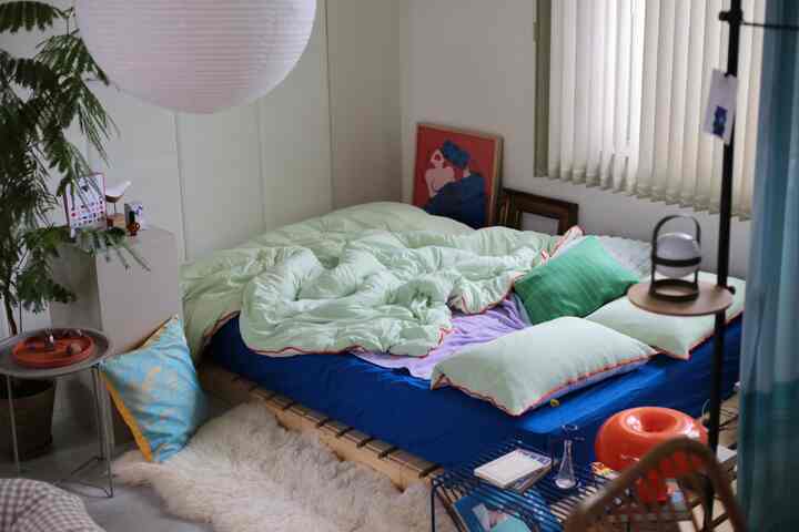 柔らかなミントグリーンの寝具と木製パレットベッドが配置されたナチュラルな寝室