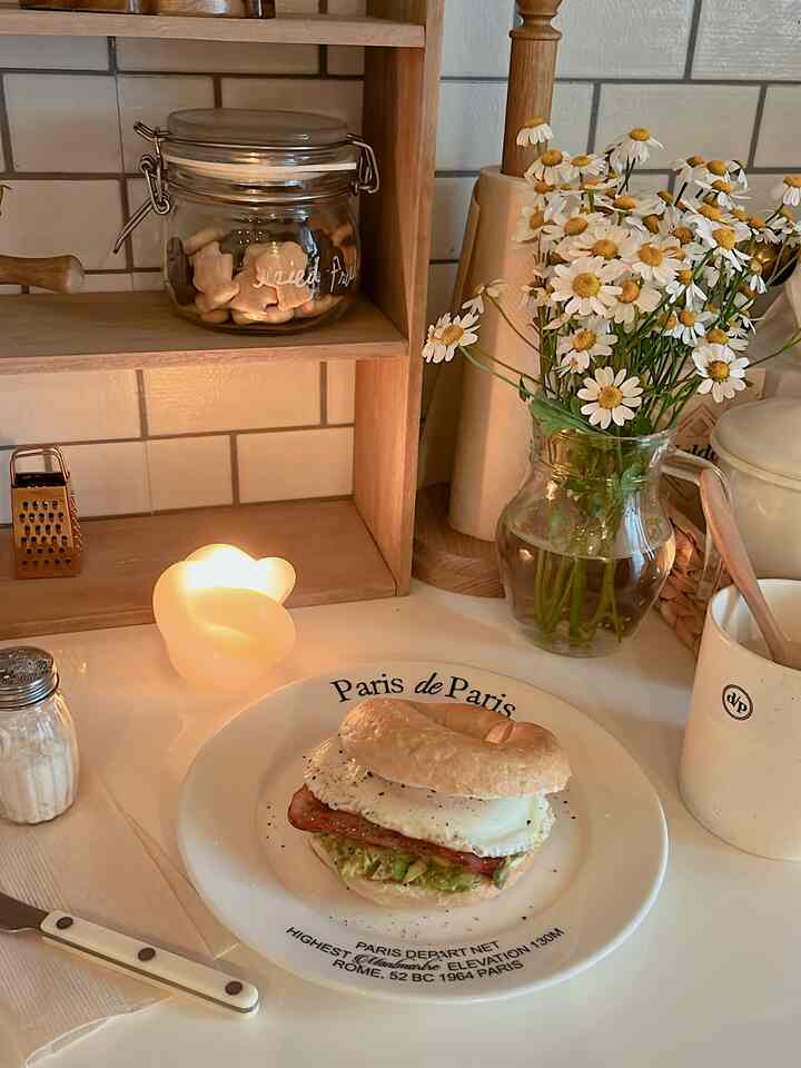 白と木目調のキッチン、花瓶とキャンドルが配置された落ち着いた一人暮らしのホームカフェの雰囲気