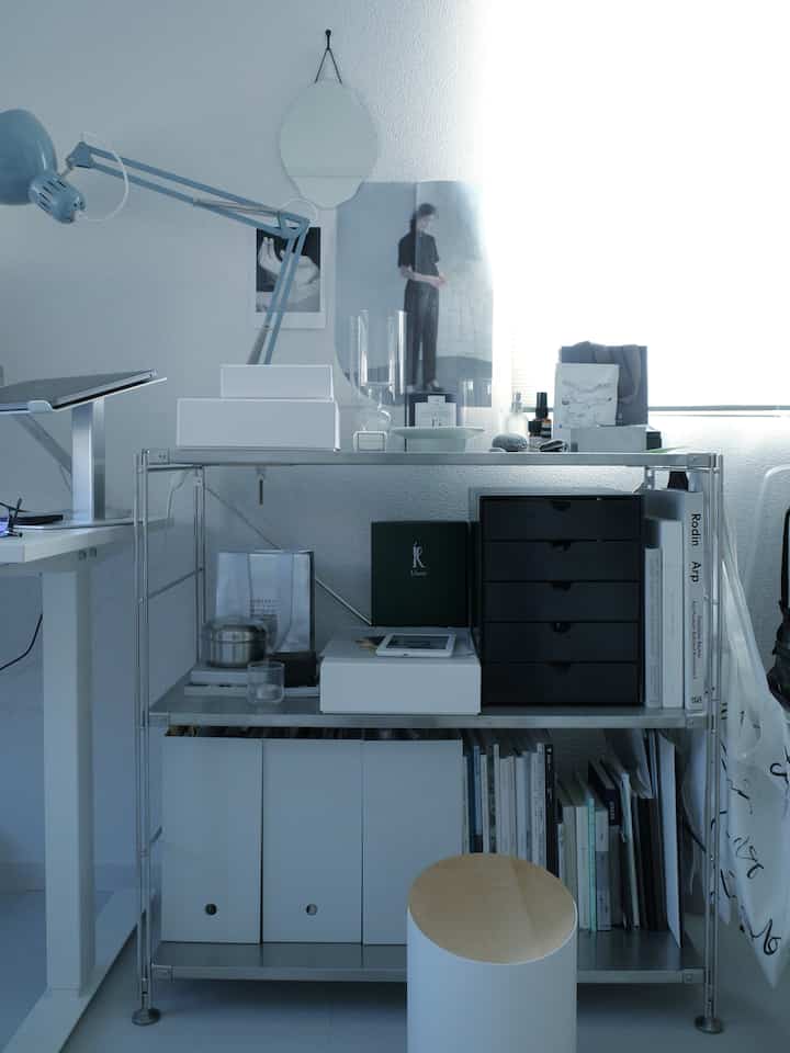 白とグレーのトーンのホームオフィス、メタルシェルフとデスクが配置されたモダンで清潔感のあるインテリア