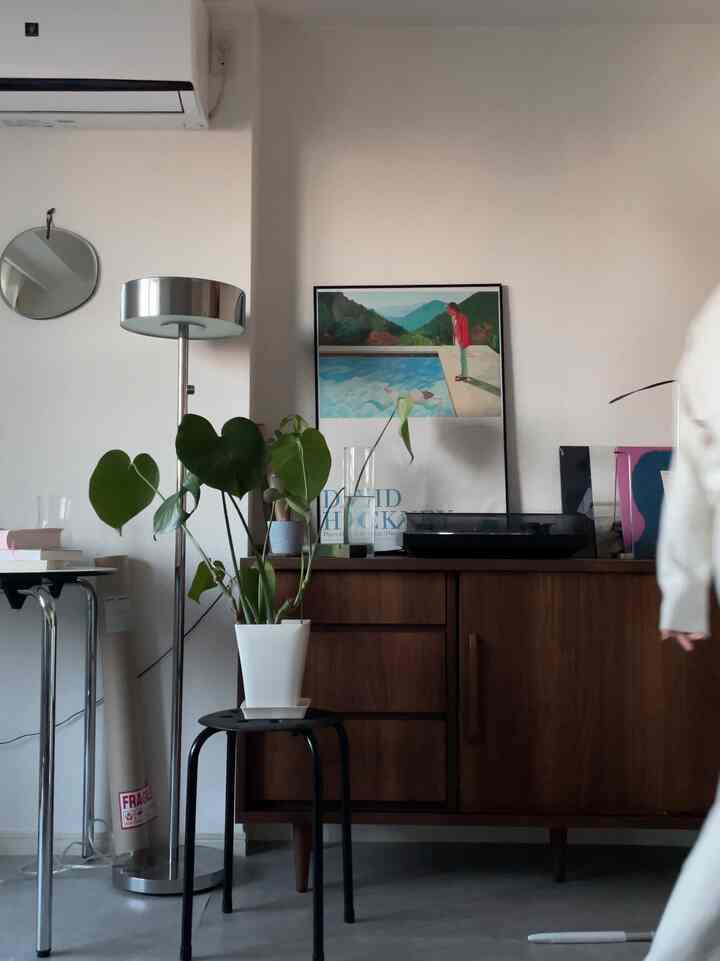 白い壁と木目調家具が調和するリビング、フロアランプと植物が温かみのある雰囲気を醸し出すレトロスタイルのインテリア