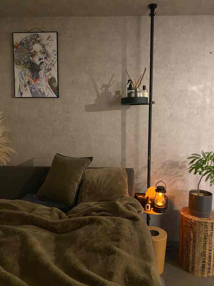 A calm olive green and wood tone bedroom featuring a cozy blanket and ambient lighting that creates a warm atmosphere