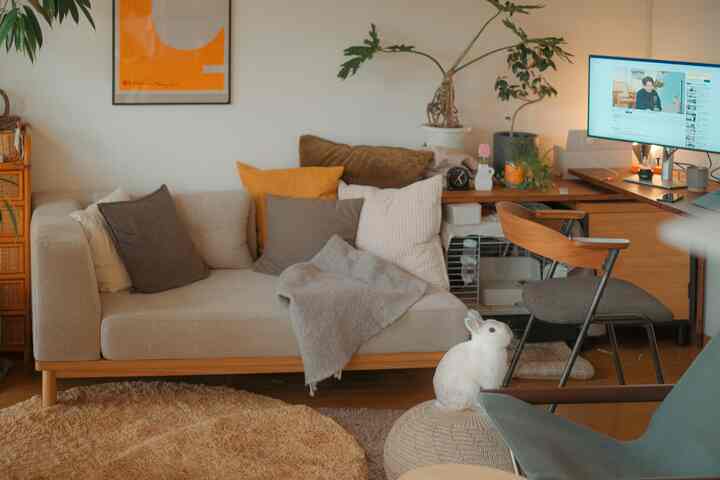 Beige and wood tone living room featuring a simple sofa with cushions and a desk with computer, creating a cozy natural interior space