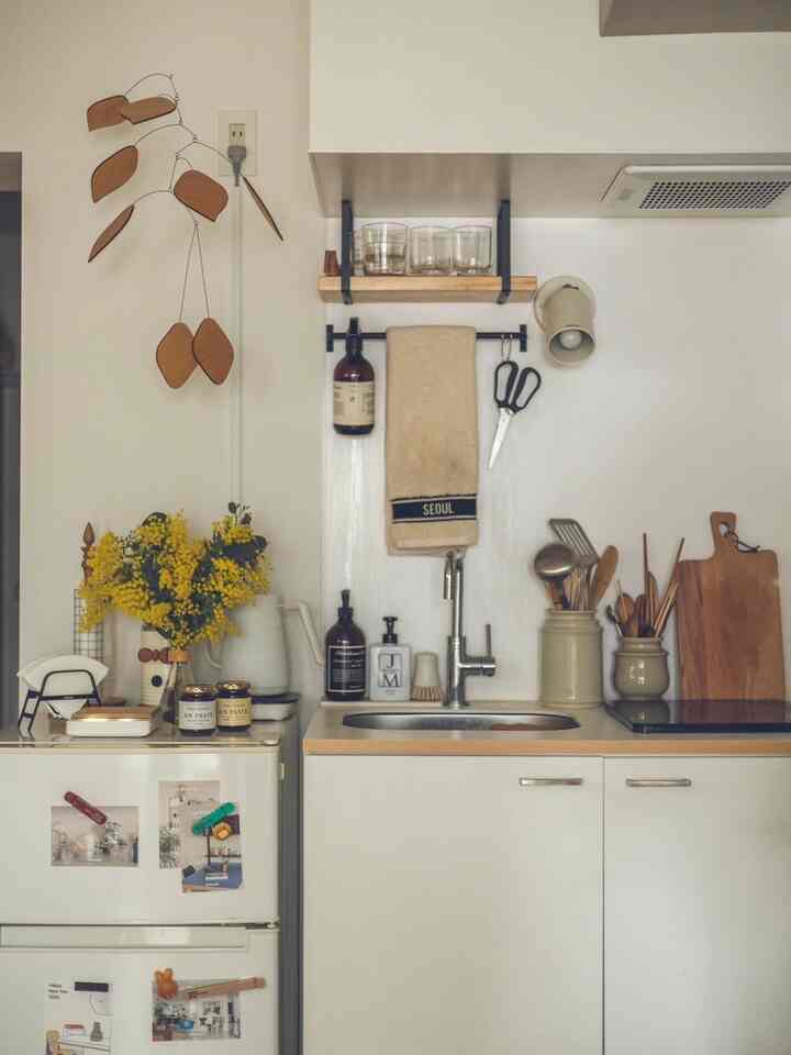 白とナチュラルウッド調のキッチン、シンクや調理器具、モビールが配置された雰囲気のあるインテリア