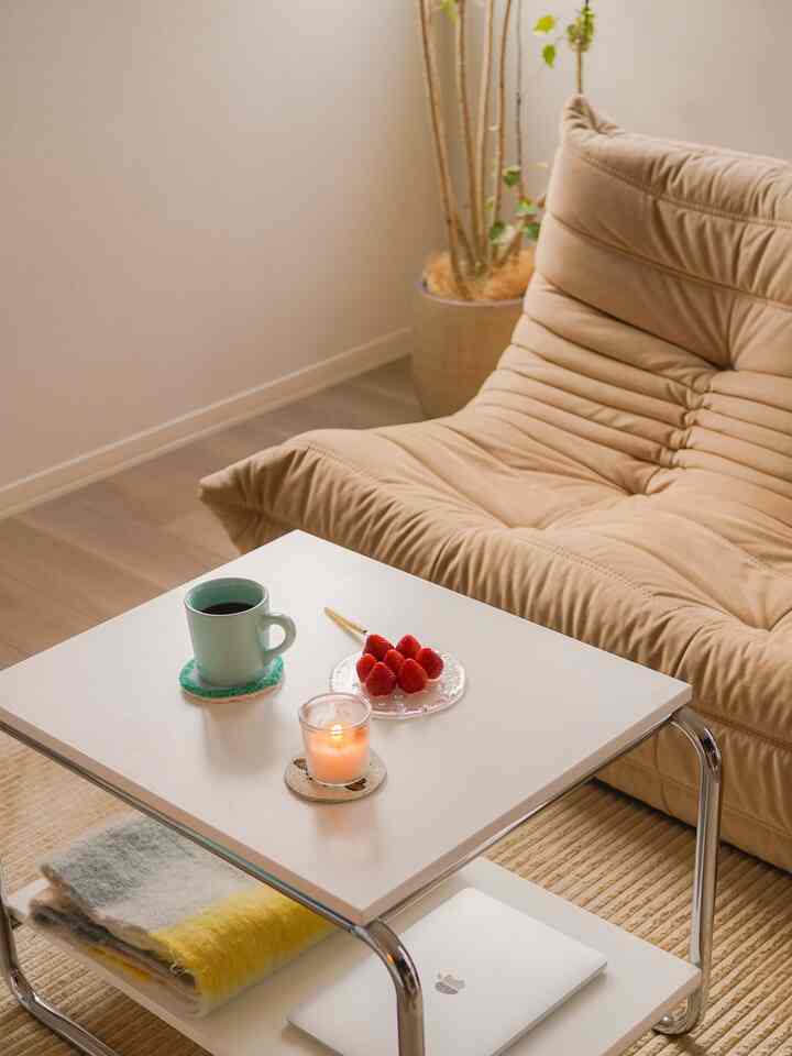 ベージュとナチュラルカラーのリビング、快適なソファとサイドテーブルにコーヒー、イチゴ、キャンドルが置かれた雰囲気のある空間