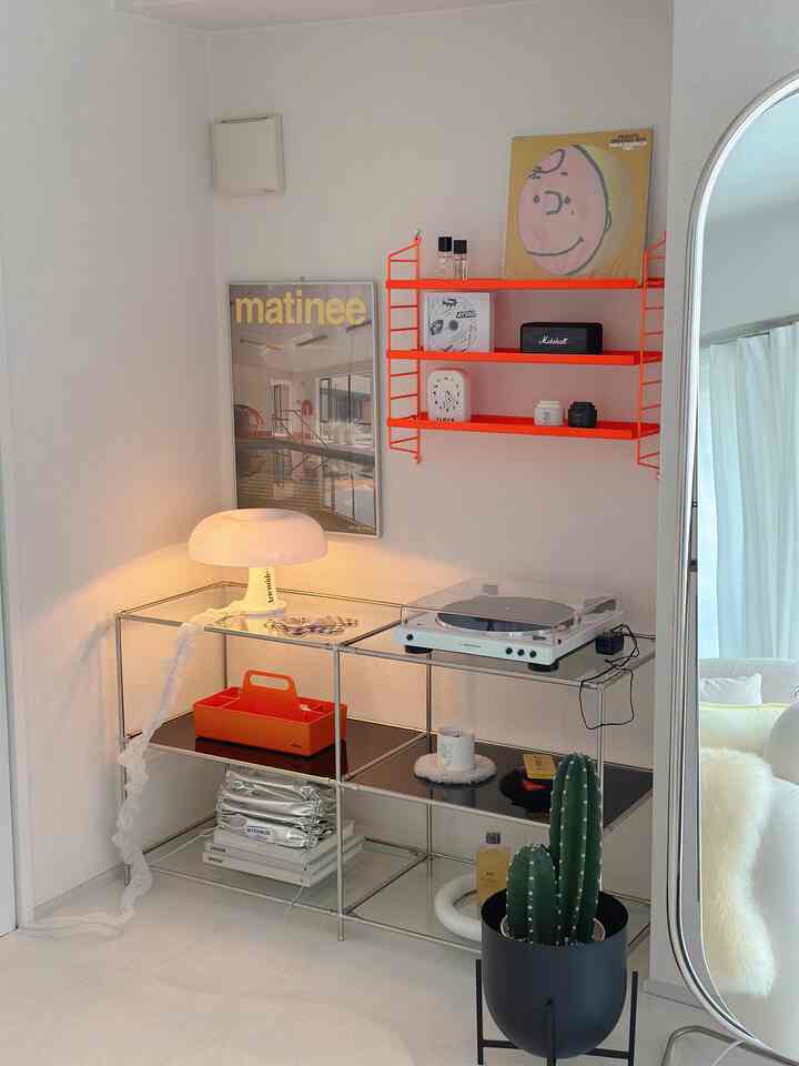 白と黄色のトーンが調和した小さなリビングの音楽コーナー、ターンテーブルとポスターが配置されたシンプルで雰囲気のあるインテリア