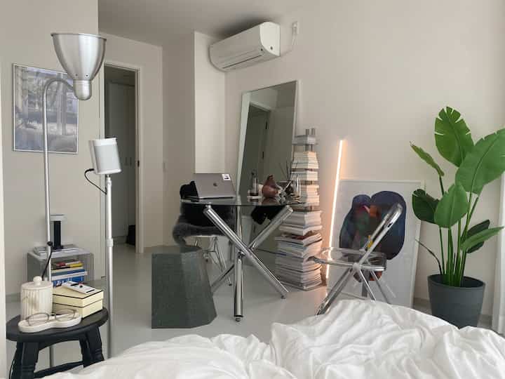 Modern home office with white background, silver metal furniture, and transparent chair arranged neatly