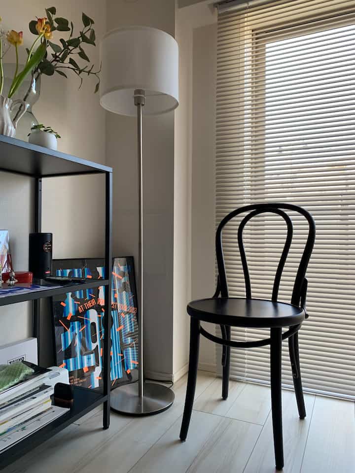 白と黒を基調とした1Kの部屋、TONチェア18とフロアランプが配置されたシンプルで落ち着いた雰囲気のインテリア