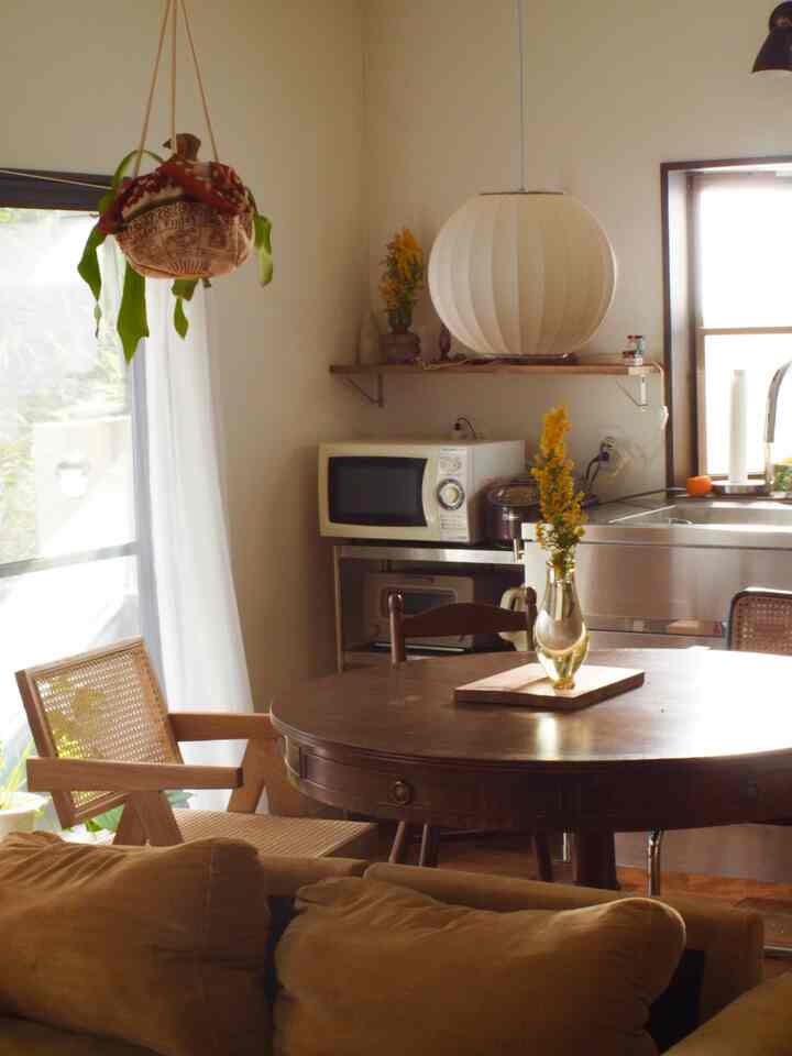 白と茶色のトーンのワンルームリビング、ミッドセンチュリーモダンのダイニングテーブルとアームチェアが配置された自然で暖かみのあるインテリア