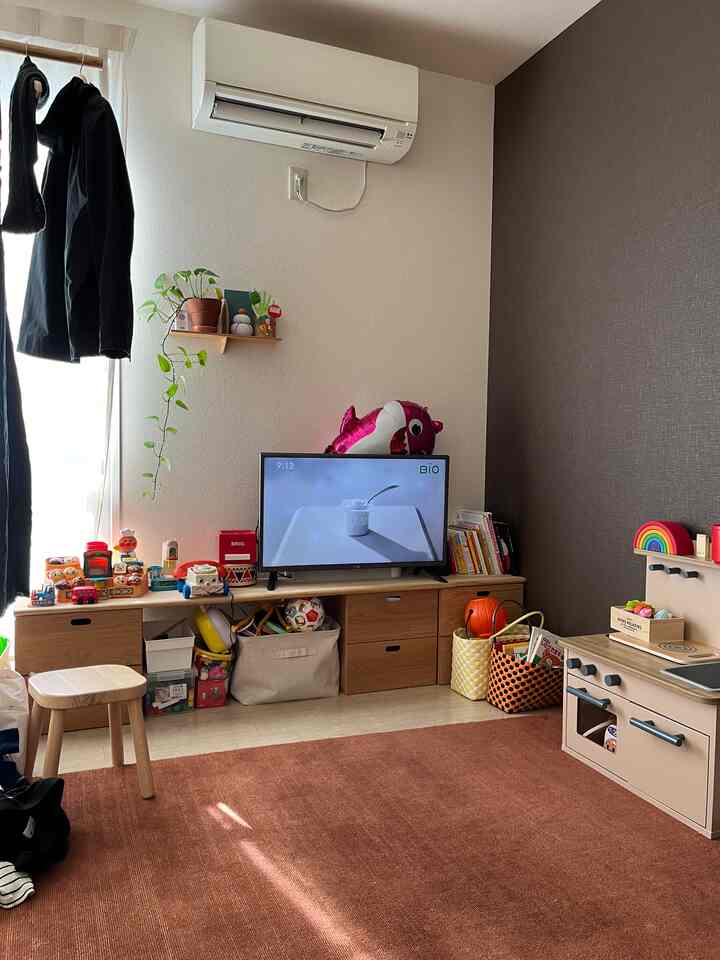 ナチュラルな色調の子供部屋、玩具収納とままごとキッチンが配置された散らかった空間