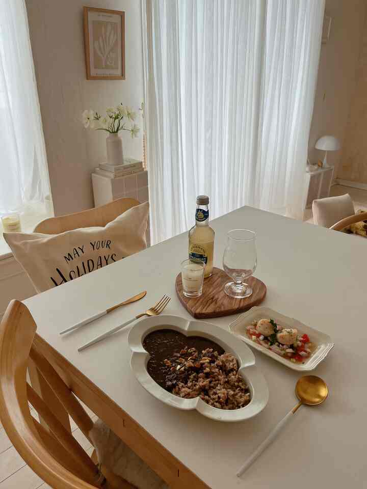 ナチュラルカラーのダイニング、白いダイニングテーブルと木目調の椅子が配置された雰囲気のある空間