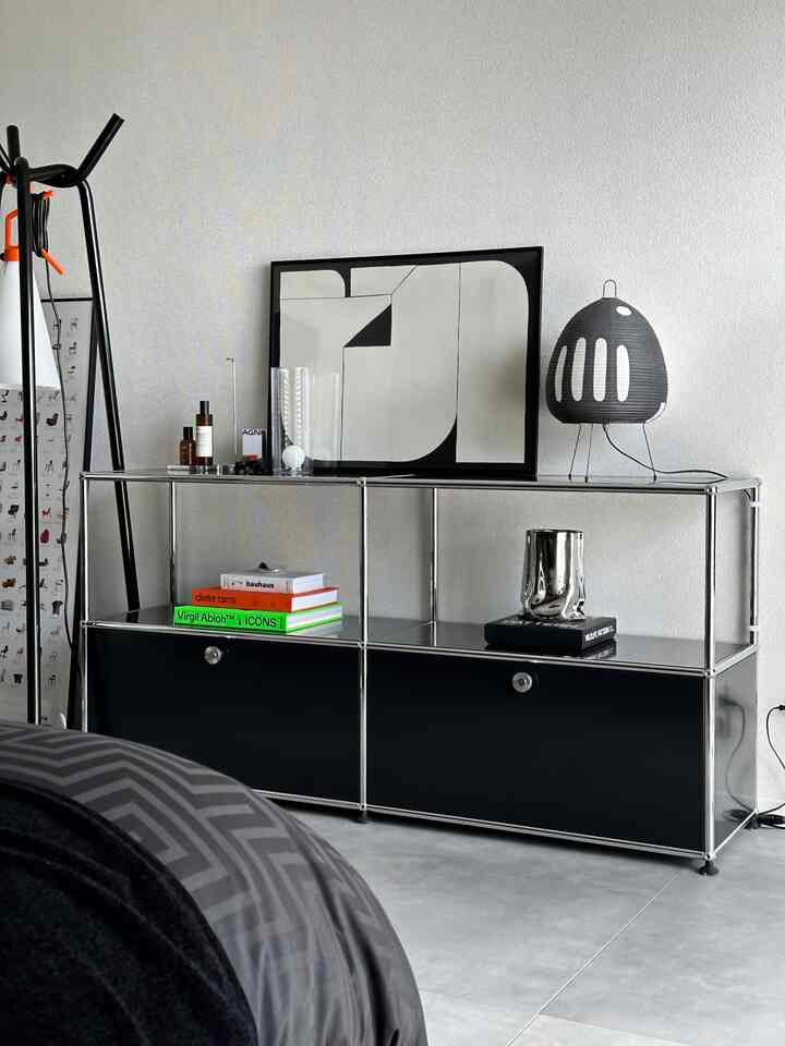 モノトーンの書斎、黒いUSM収納、抽象画の額縁とテーブルランプが配置された清潔感のあるミニマルなインテリア