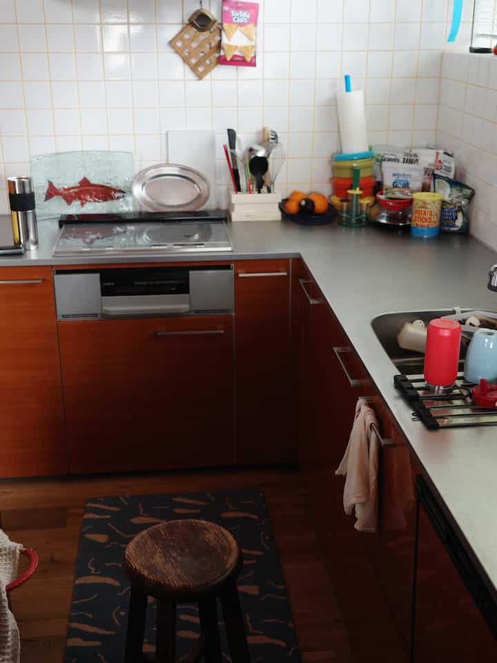 ウッド調とシルバーのL字型キッチン、木製スツールと調理器具が配置された雰囲気のあるキッチン