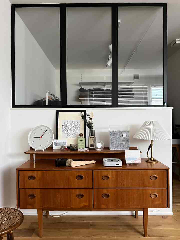 Cozy mid-century modern space featuring a natural wood tone sideboard against a white wall