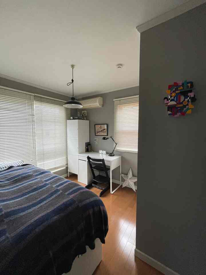 Modern bedroom with gray walls, white furniture, and wood tone flooring