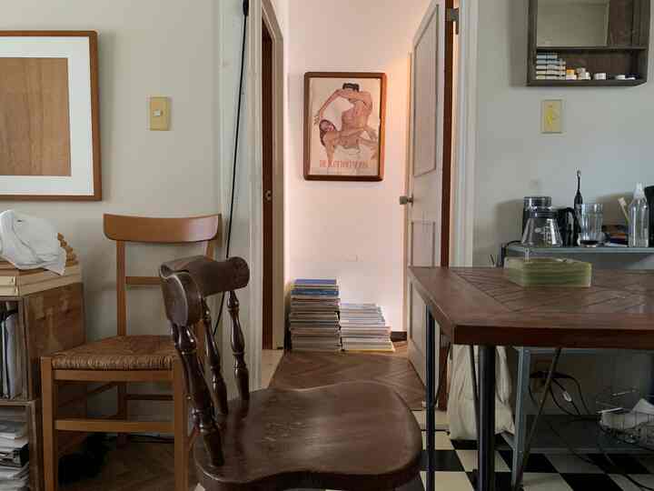 ナチュラルな木目調が調和する狭い廊下と隣接空間、ヴィンテージ感のある木製家具と本棚が配置された雰囲気のあるインテリア