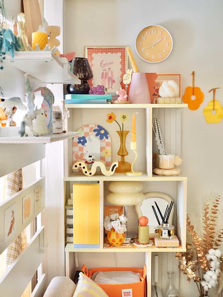 白と黄色の色調が調和した北欧風の棚、花瓶やオブジェが配置された雰囲気のあるインテリア