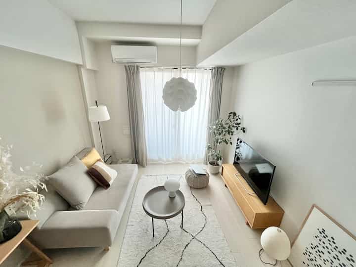 Bright white and wood-toned compact living room with gray sofa and coffee table, featuring a natural modern style