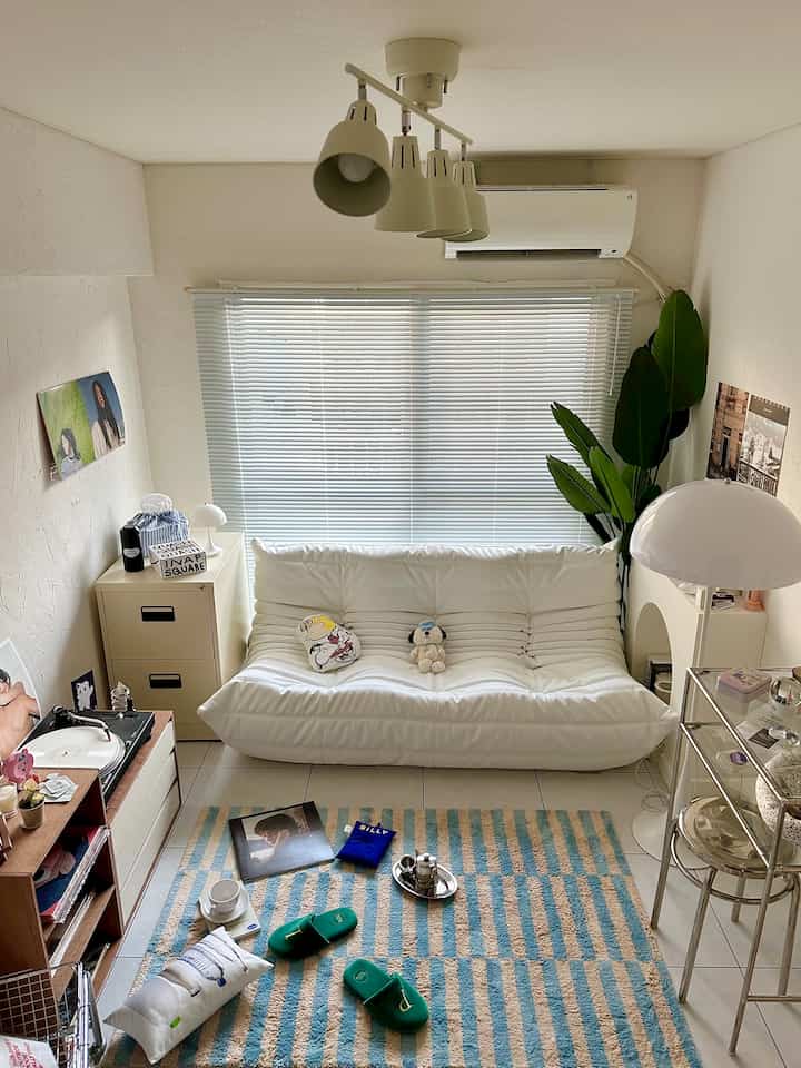 Bright and clean single household living room with white sofa and blue-beige striped rug