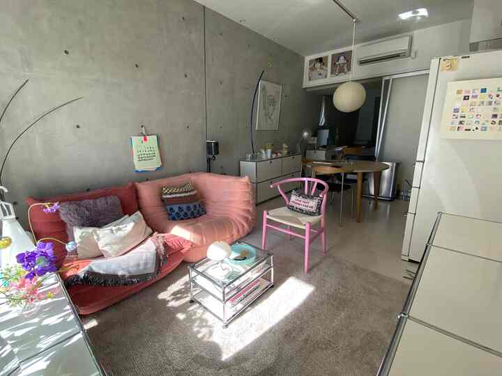 白とピンクの色調のリビング・ダイニングルーム、ピンクのソファと丸いダイニングテーブルが配置されたモダンでナチュラルなインテリア