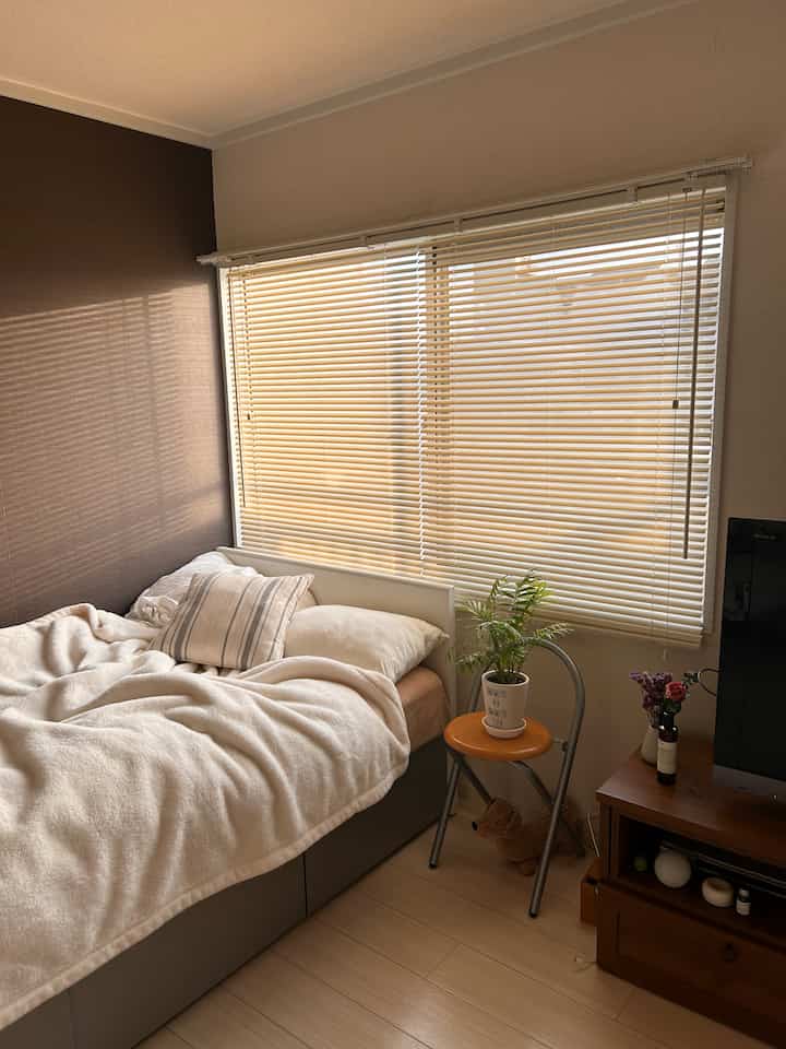 Natural beige-toned bedroom with large window covered by blinds, creating a cozy and serene atmosphere