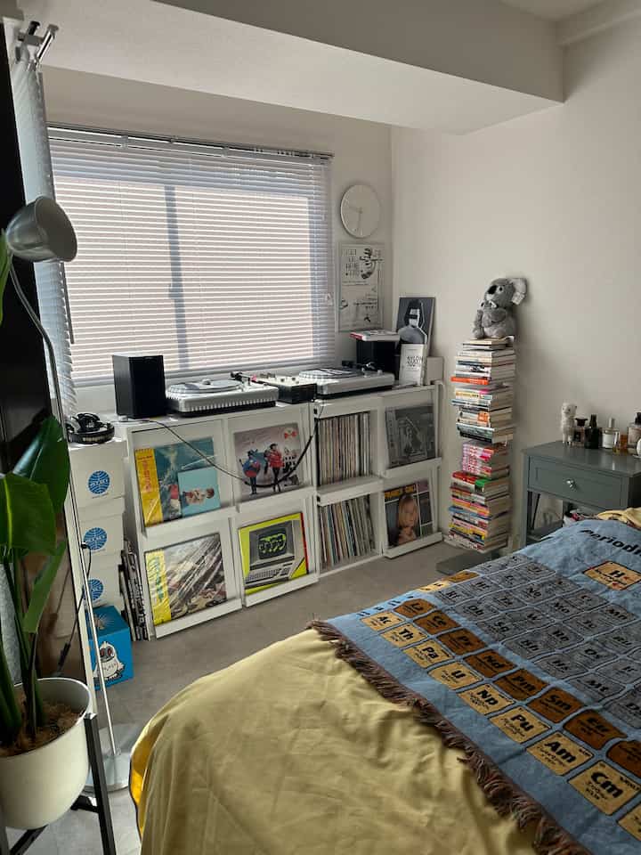 明るいホワイトのモダンな一人暮らし用寝室、音楽機器と本棚が配置された雰囲気のある空間