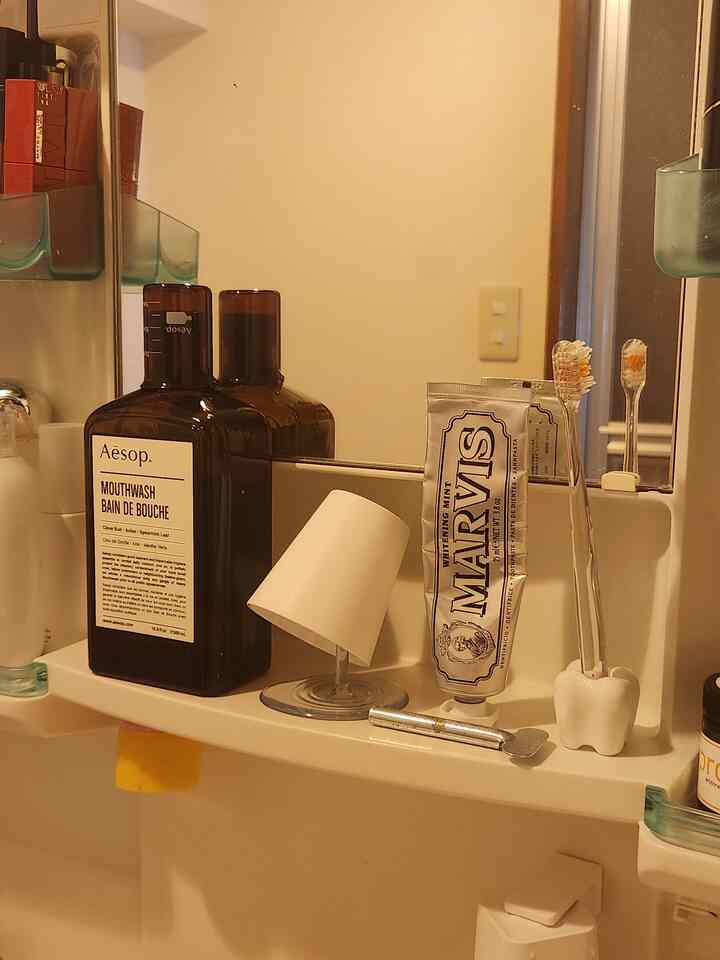 温かみのあるライトブラウンとホワイトの色調のバスルーム洗面台、鏡と整理された洗面用品が配置された雰囲気のあるインテリア