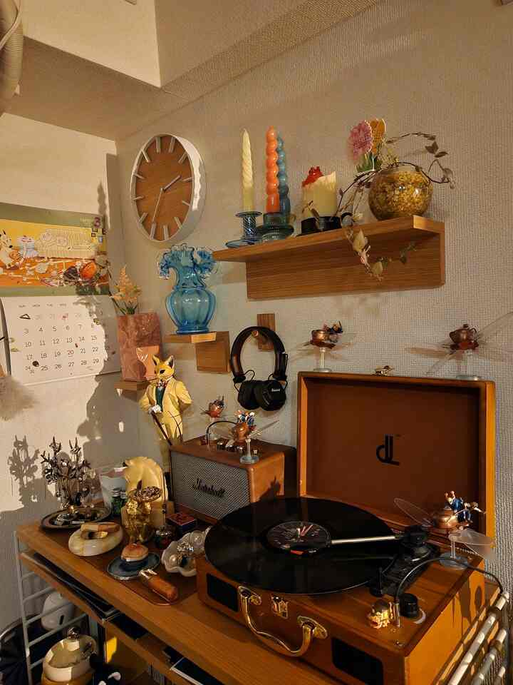 木目調の小さな室内、ヴィンテージオーディオやキャンドル、植物が配置された雰囲気のあるインテリア