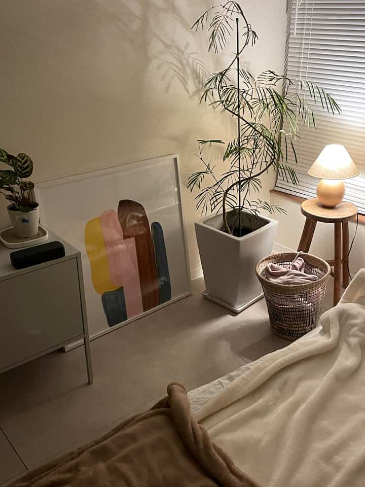 ベージュと木目調の寝室、テーブルランプと植物が落ち着いた雰囲気を醸し出す印象的な空間