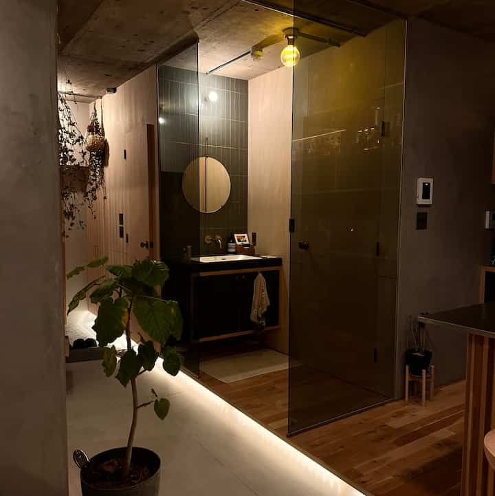 ナチュラルな色調のバスルーム、ガラスパーティションと化粧台、間接照明が洗練された雰囲気を演出する空間