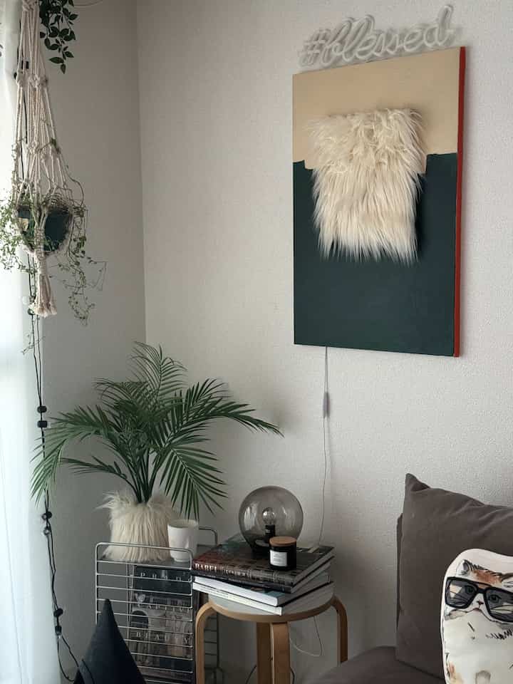 白と緑のトーンの1LDKリビング、自然な植物とシンプルなサイドテーブルが配置された落ち着いた空間