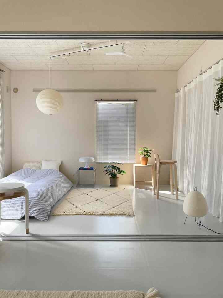 白とナチュラルカラーの寝室、ペンダントライトとフロアランプが配置されたミニマルで落ち着いたインテリア