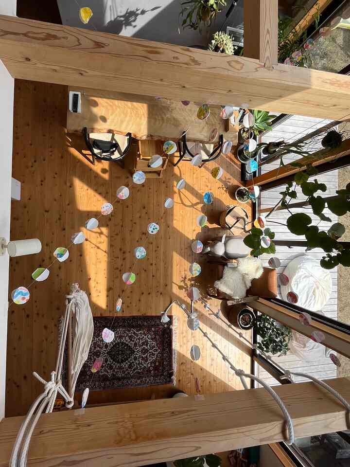 自然な木目調の床と梁、カラフルなガーランドが配置された明るく広々としたリビングルーム