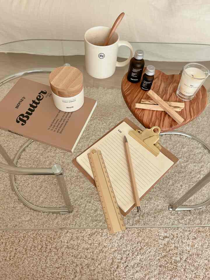 ブラウンのナチュラルトーンのリビングダイニングテーブル、ガラステーブル上にアロマキャンドルとハンドクリーム、筆記用具が配置された雰囲気のあるインテリア