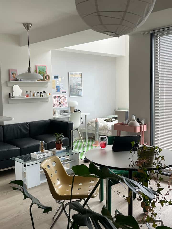 Modern 6-tatami living and bedroom space with white walls and ceiling, black sofa, glass coffee table, desk and bed arranged in cozy single household