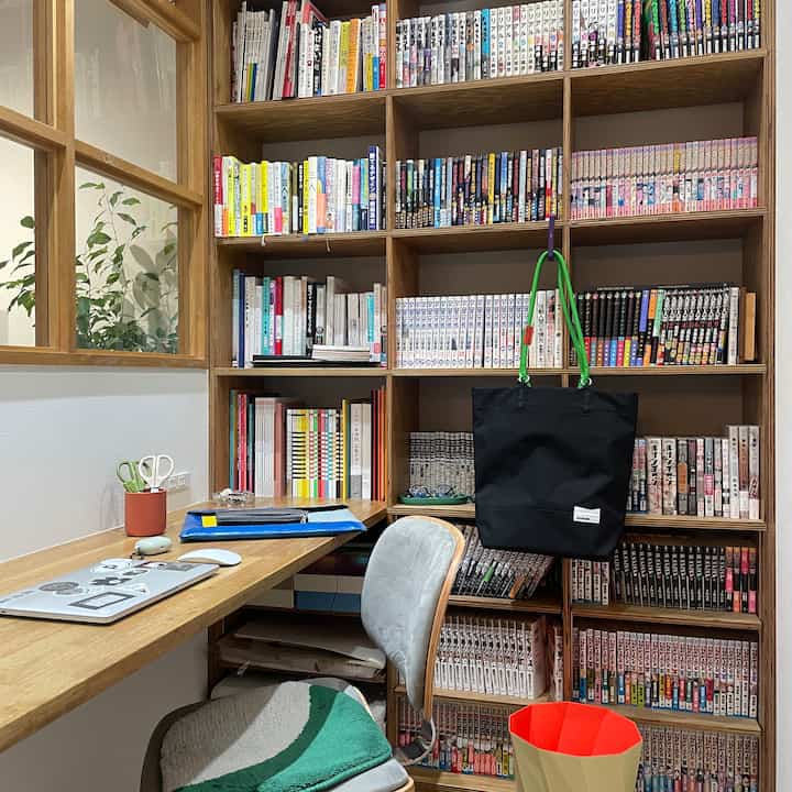 ナチュラルな木目調の書斎、整然とした本棚とデスク、グレーの椅子が配置された落ち着いた雰囲気のインテリア