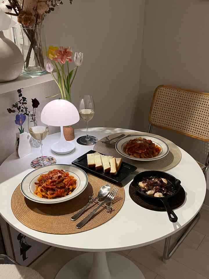 白と茶色の北欧風ダイニング、シンプルな丸テーブルとラタンチェアが配置された雰囲気のある空間